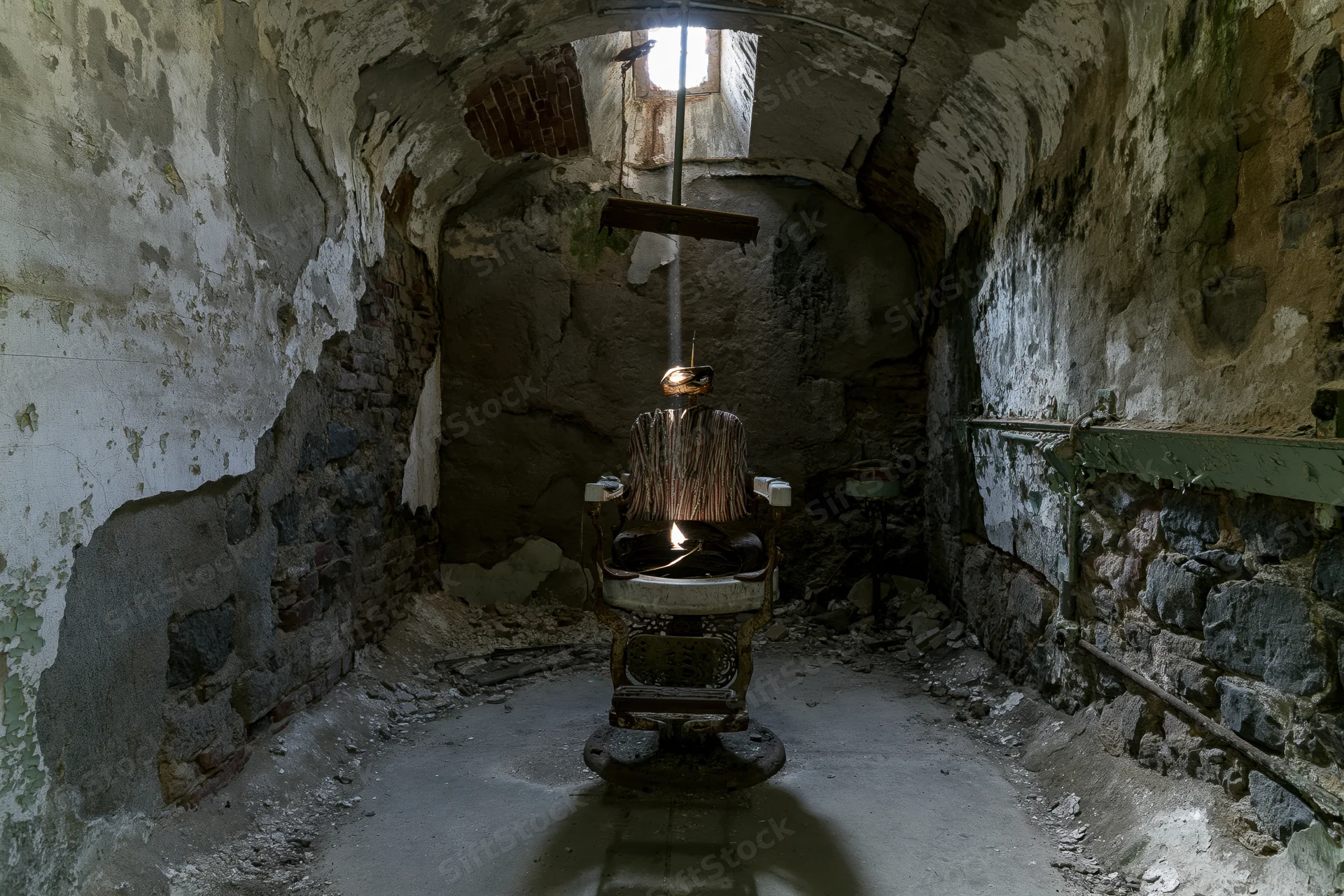 Decayed vintage dental chair centered in a crumbling stone vaulted room with light streaming through a high window