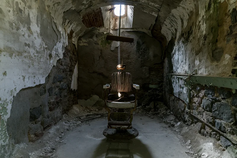 Decayed vintage dental chair centered in a crumbling stone vaulted room with light streaming through a high window