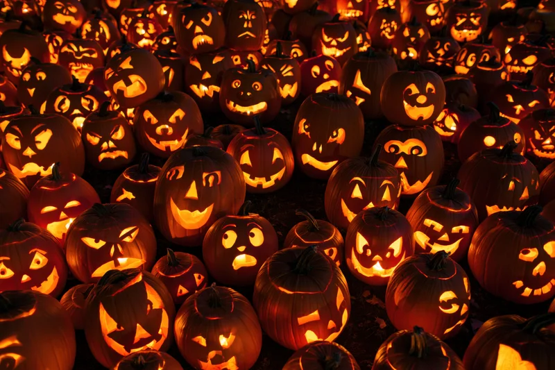 Dozens of carved jack-o-lanterns glowing in the dark at night