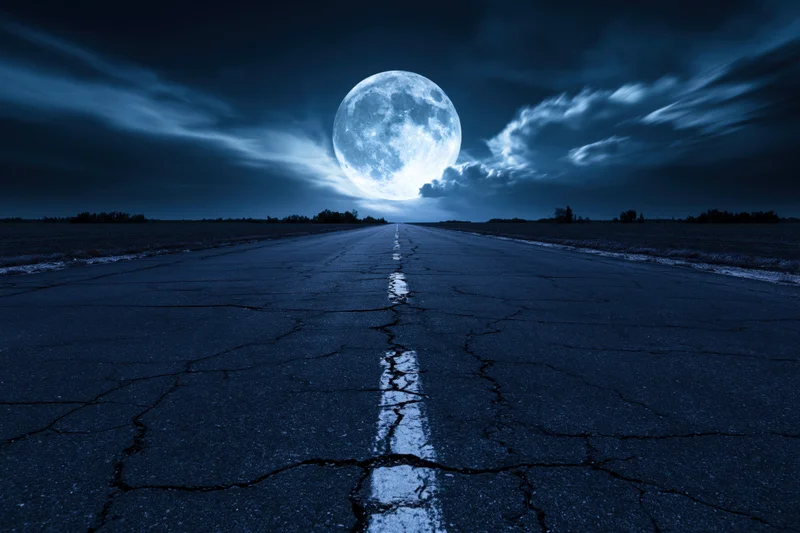 Cracked asphalt road stretching straight to the horizon under a full moon at night