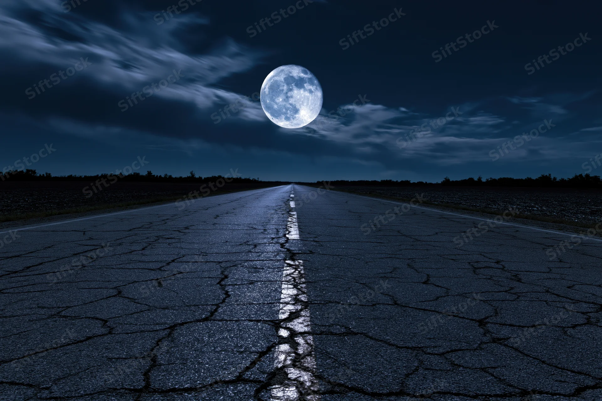 Cracked asphalt road stretching to the horizon under a full moon at night