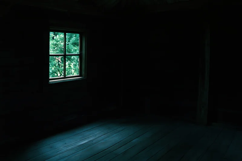 Dark wooden room with a small four-pane window showing green forest view