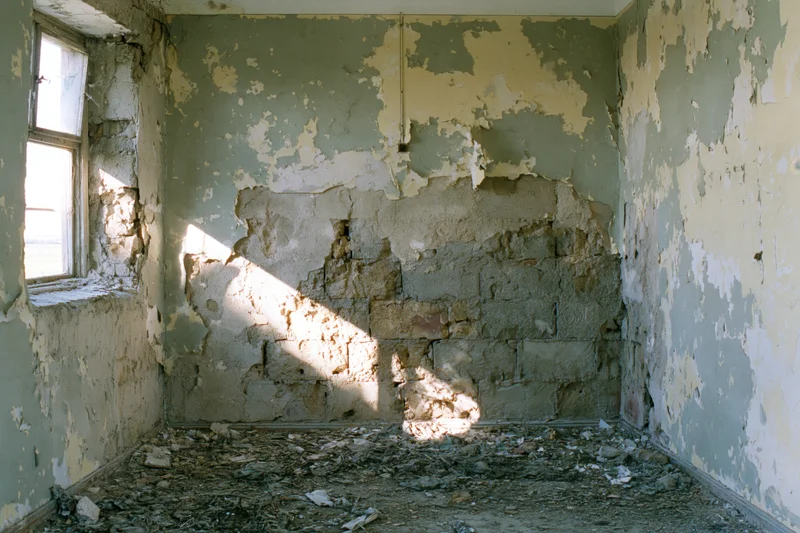 Empty interior of a deteriorated abandoned building with peeling paint and exposed brick walls
