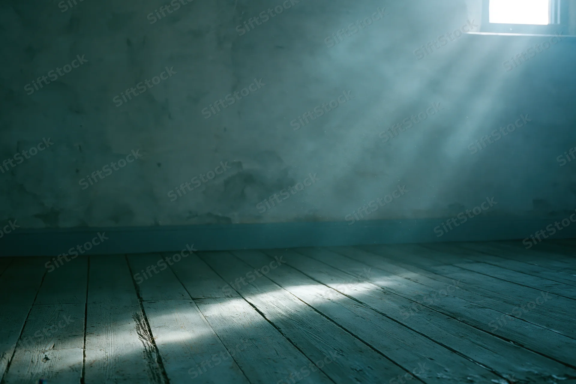 Empty room with weathered wooden floorboards and rough concrete wall, sunbeam through window casting light and shadow