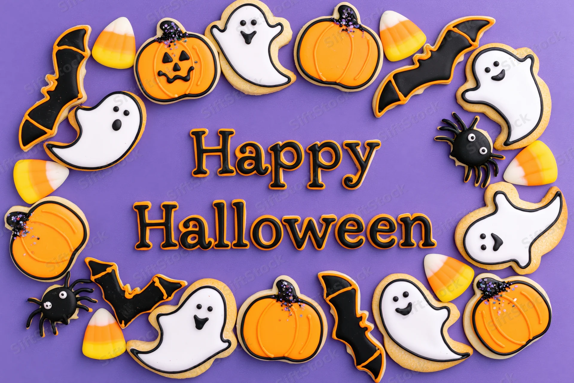 Decorated halloween sugar cookies arranged in a circular frame around happy halloween text on purple background