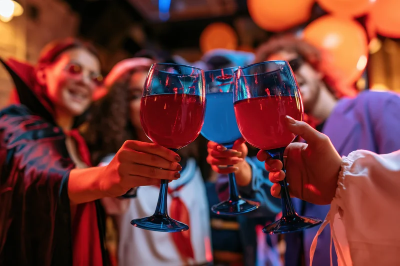 People in halloween costumes toasting with wine glasses at a party