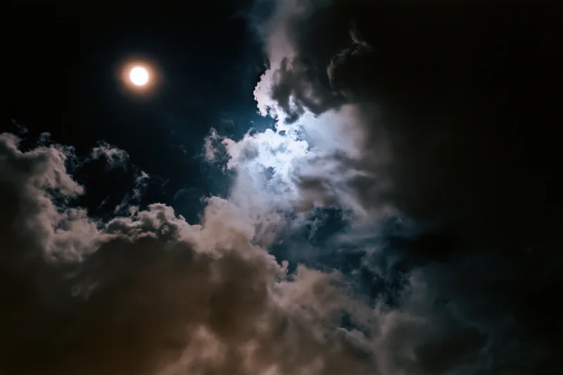 Full moon glowing through thick billowing clouds at night