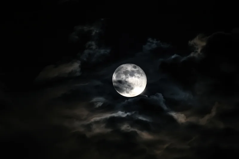 Full moon glowing through churning storm clouds in dark night sky