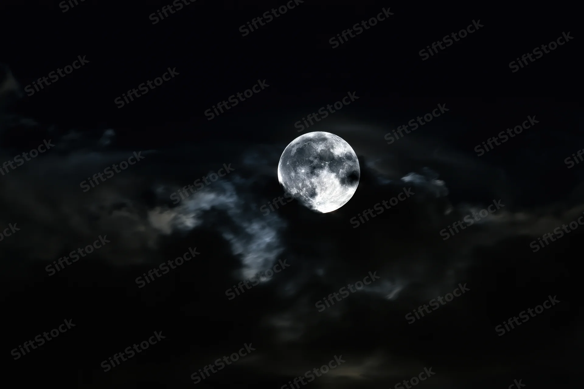 Full moon glowing through churning storm clouds in dark night sky
