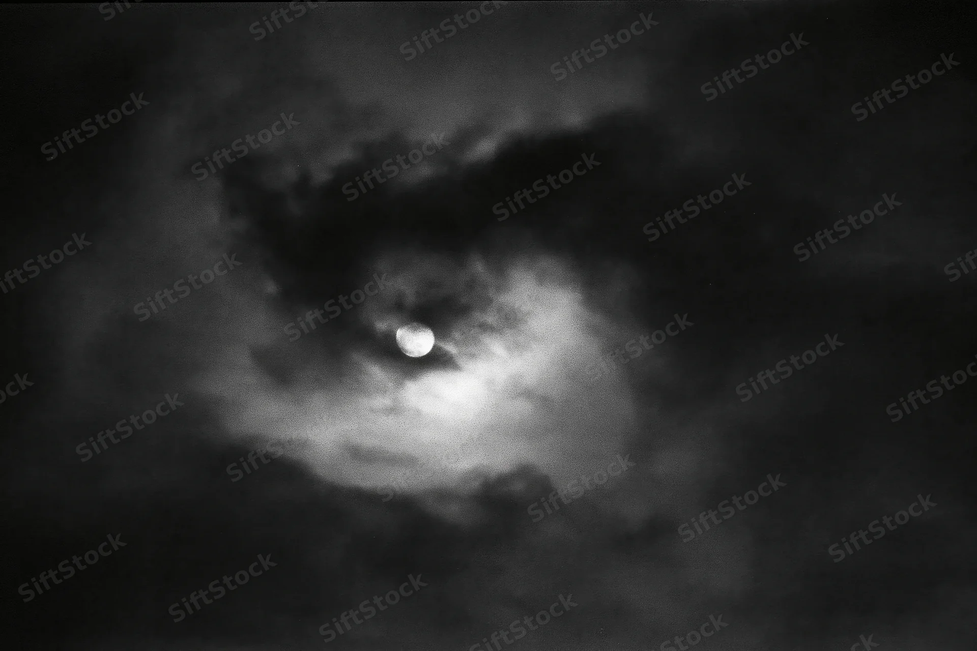 Full moon partially hidden by thick storm clouds in the night sky