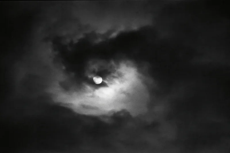 Full moon partially hidden by thick storm clouds in the night sky