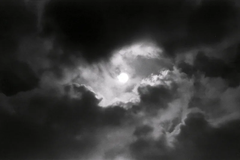 Full moon glowing through thick storm clouds in the night sky