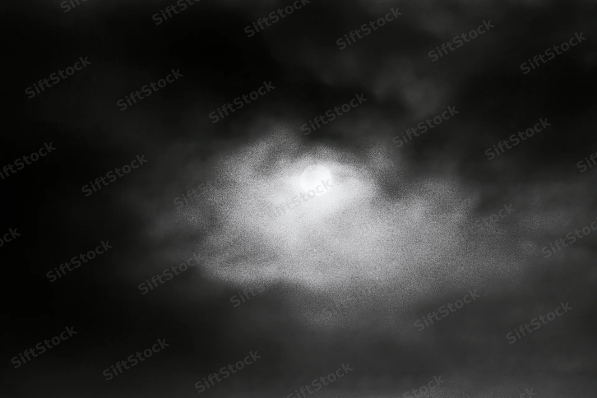 Full moon glowing through thick storm clouds in the night sky