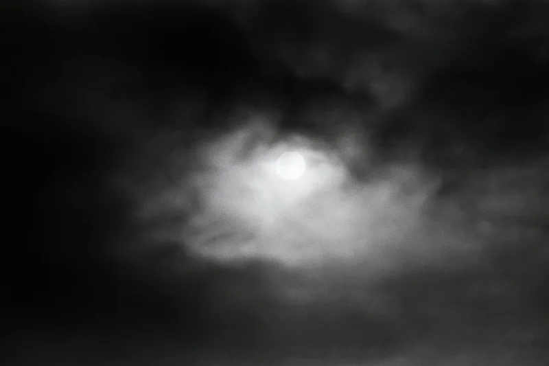 Full moon glowing through thick storm clouds in the night sky