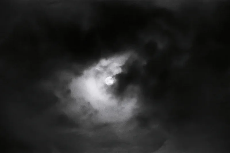 Full moon glowing through thick storm clouds in the night sky