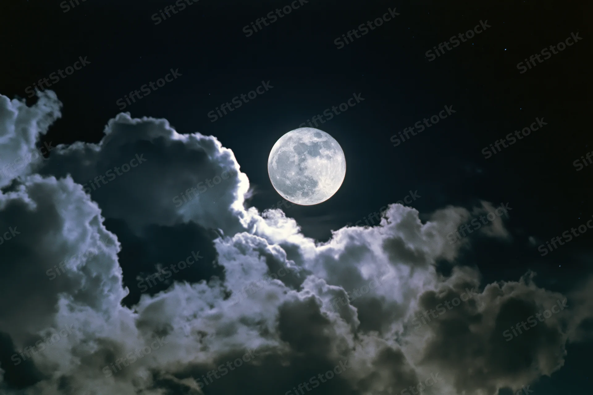 Full moon glowing in dark sky above billowing clouds