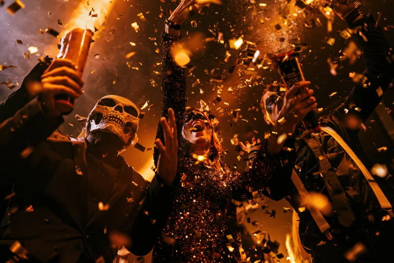 Costumed partygoers celebrating with beer and confetti indoors