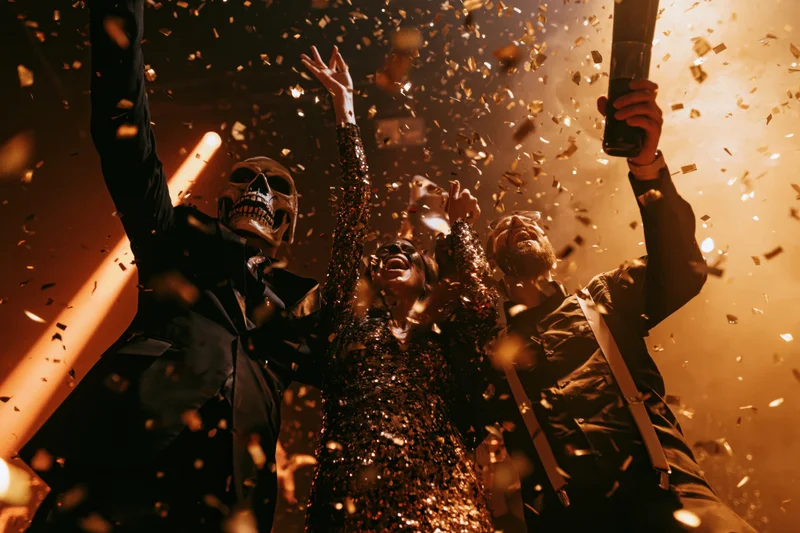 Costumed partygoers celebrating with confetti and drinks indoors