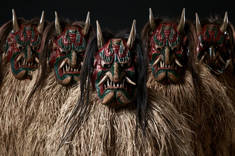 Row of traditional japanese namahage demon figures with horned masks and straw costumes standing in line against dark background