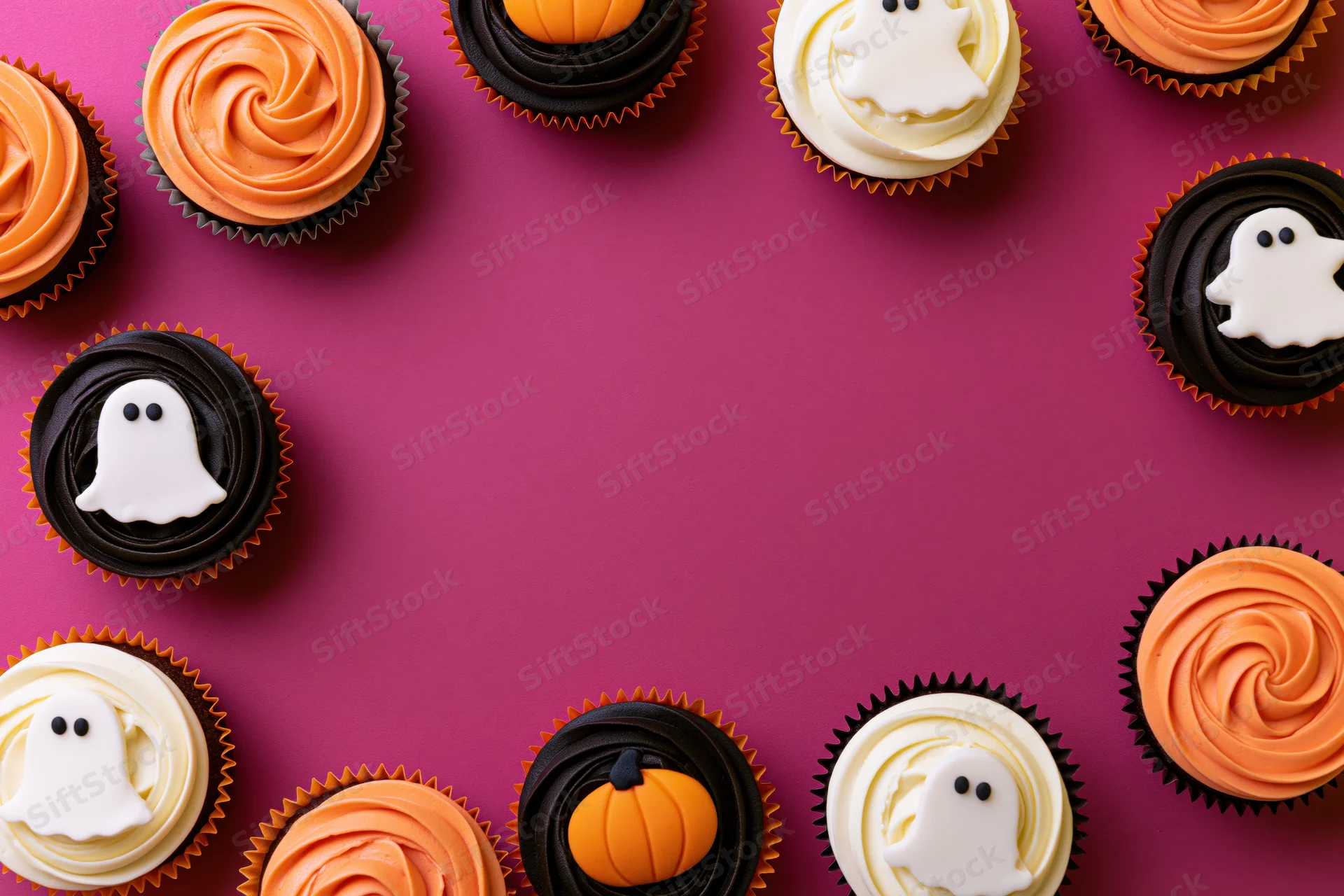 Halloween cupcakes with ghost and pumpkin decorations arranged in a border on a purple surface