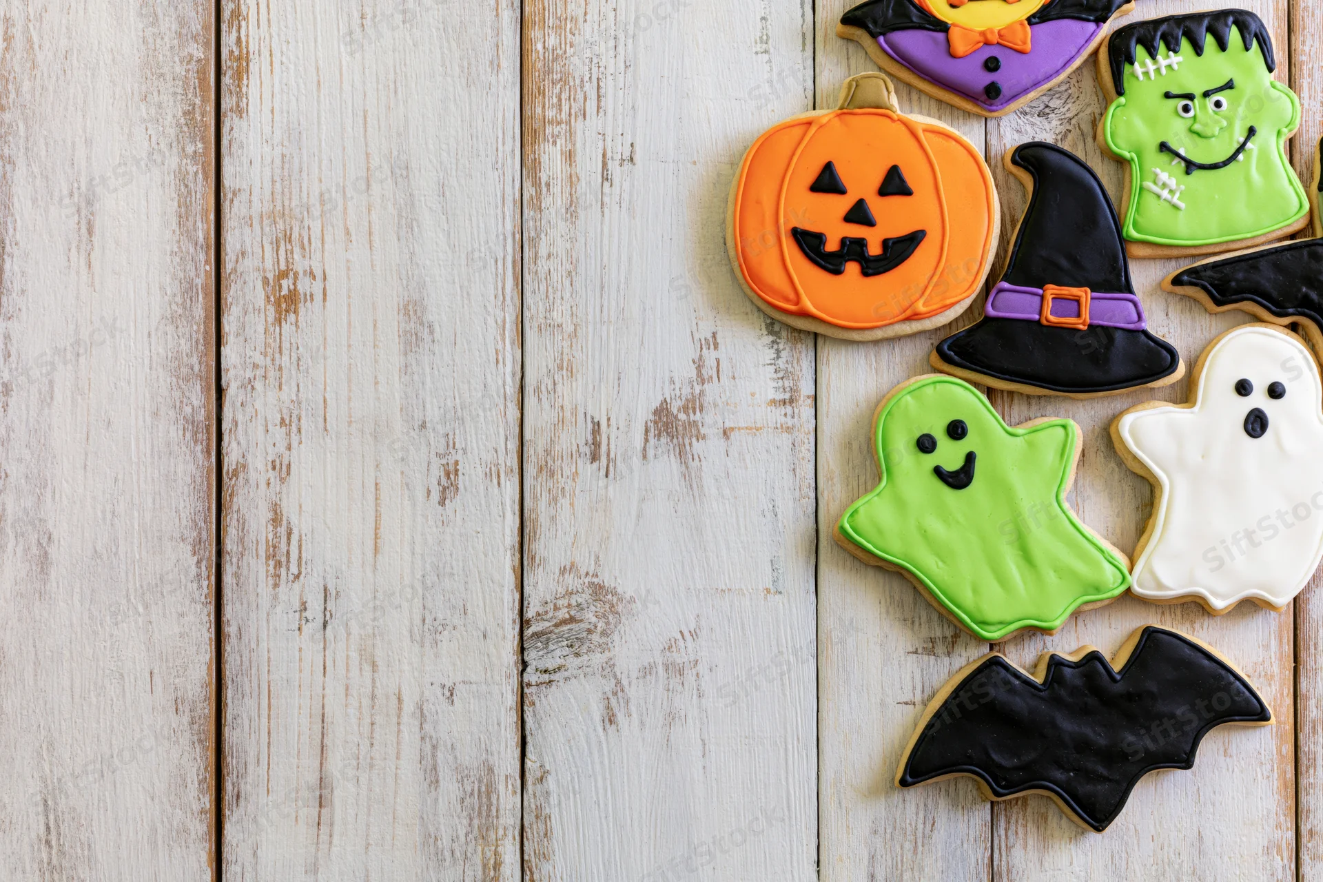 Halloween decorated sugar cookies arranged on a rustic wooden surface with copyspace