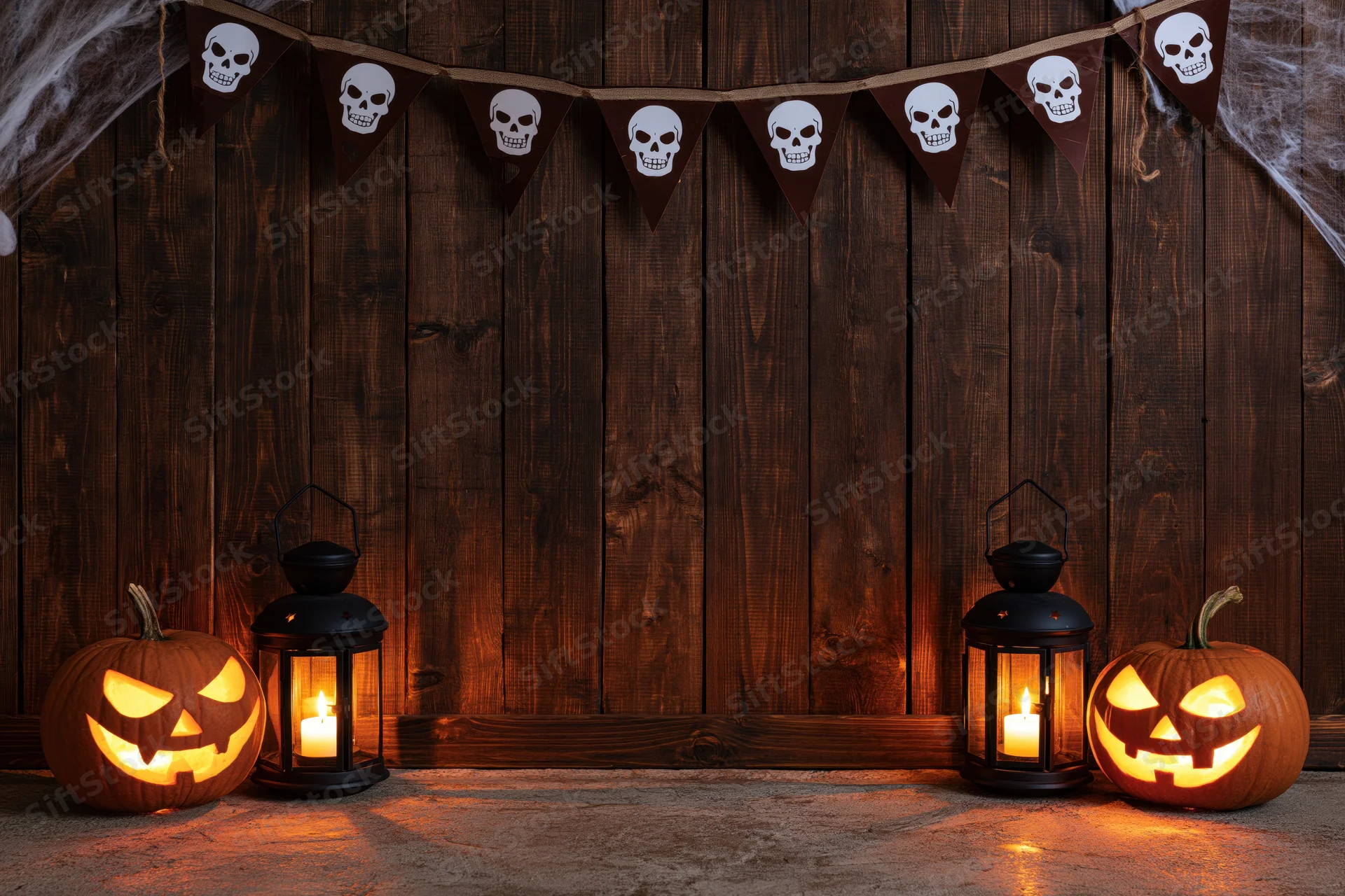 Carved pumpkins and lit lanterns arranged against a dark wooden plank wall with skull banner above