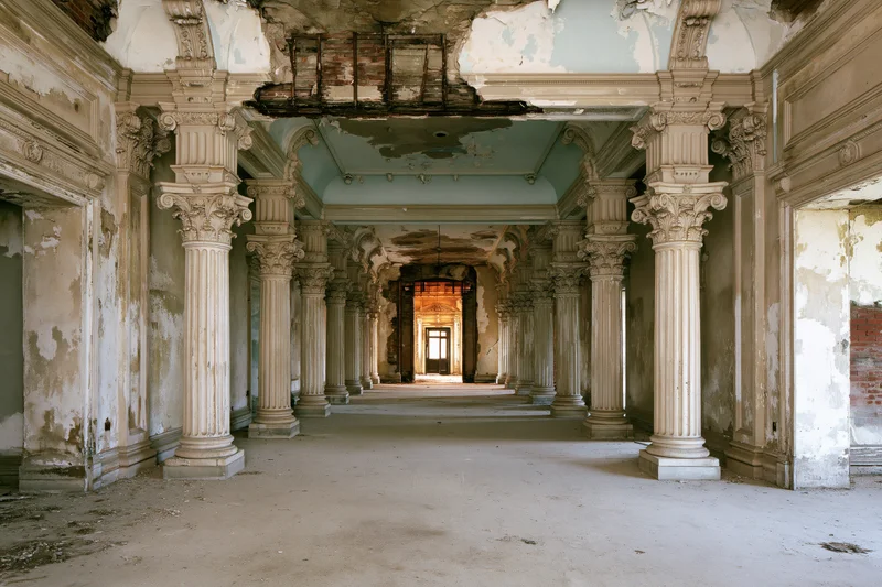 Grand abandoned colonial hall with decaying columns and peeling plaster interior