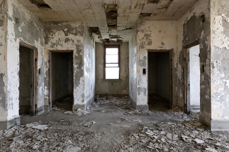 Abandoned room interior with crumbling walls and debris on floor, multiple doorways and a window letting in light