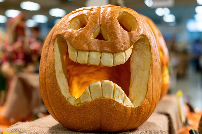 Carved pumpkin with smiling face and glowing light inside on display in store