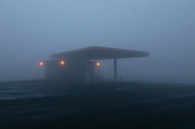 Isolated gas station with glowing orange lights under a foggy twilight sky