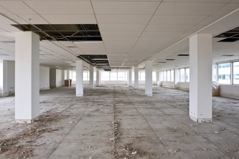 Empty commercial office space mid-renovation with exposed ceiling and concrete floor
