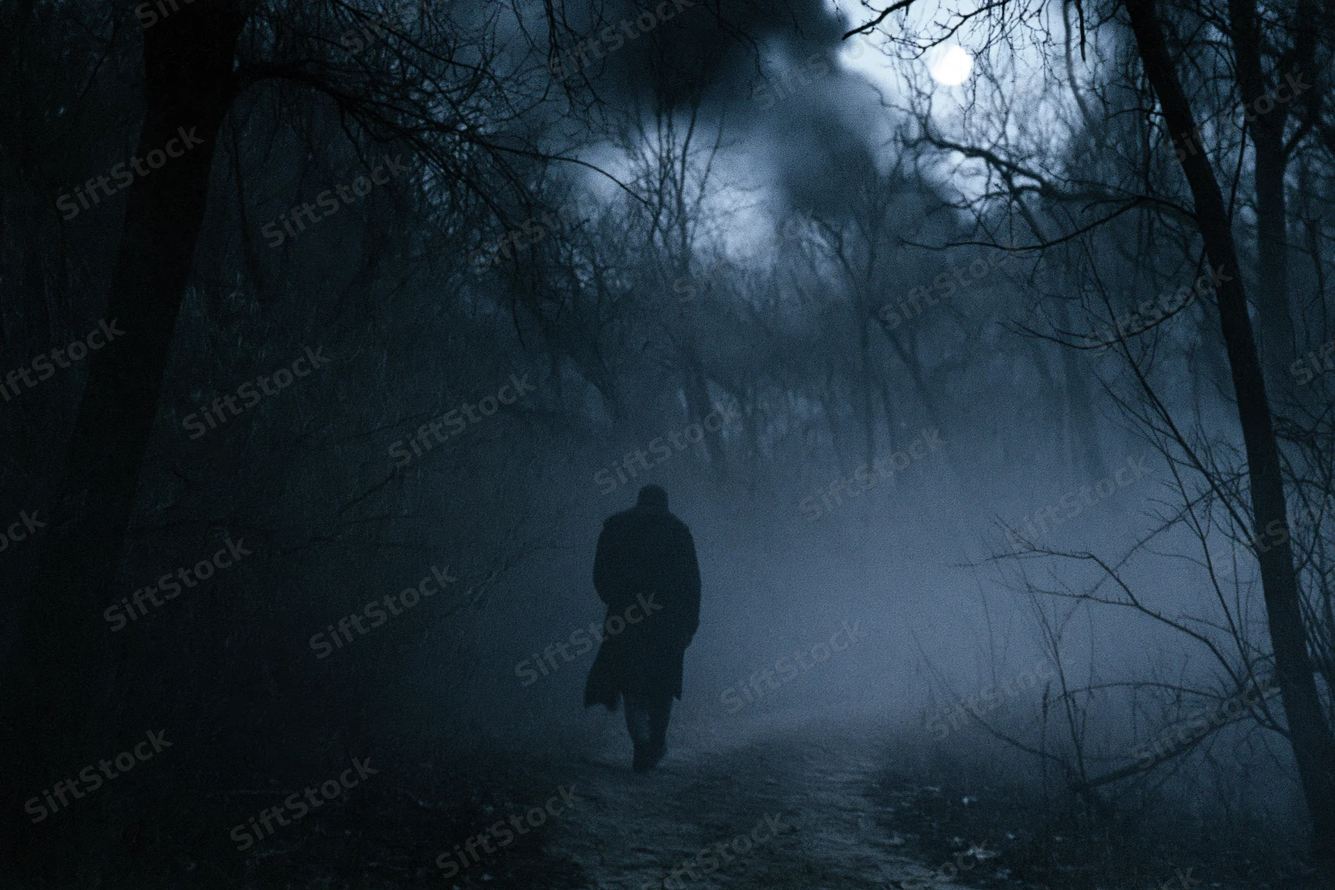 Man walking away along a narrow path through a foggy forest at night