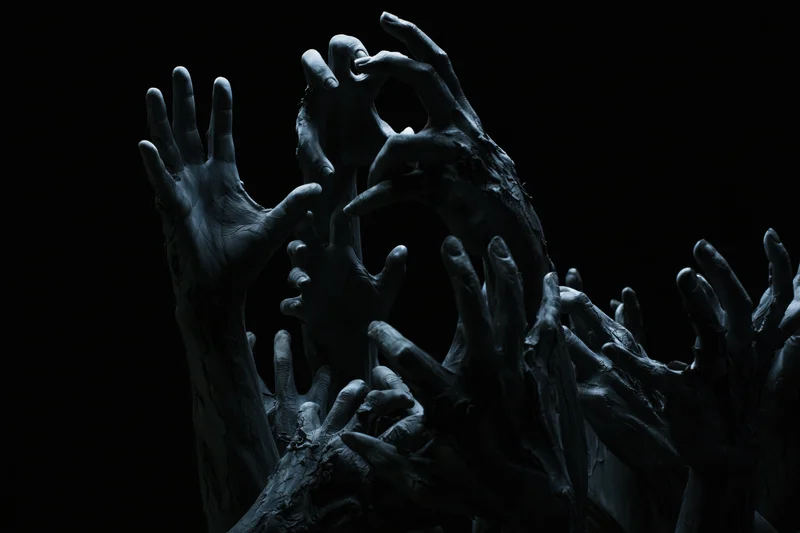 Decayed hands reaching upward from darkness