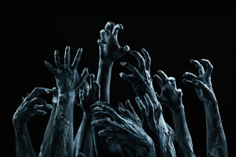 Decayed zombie hands reaching upward from darkness
