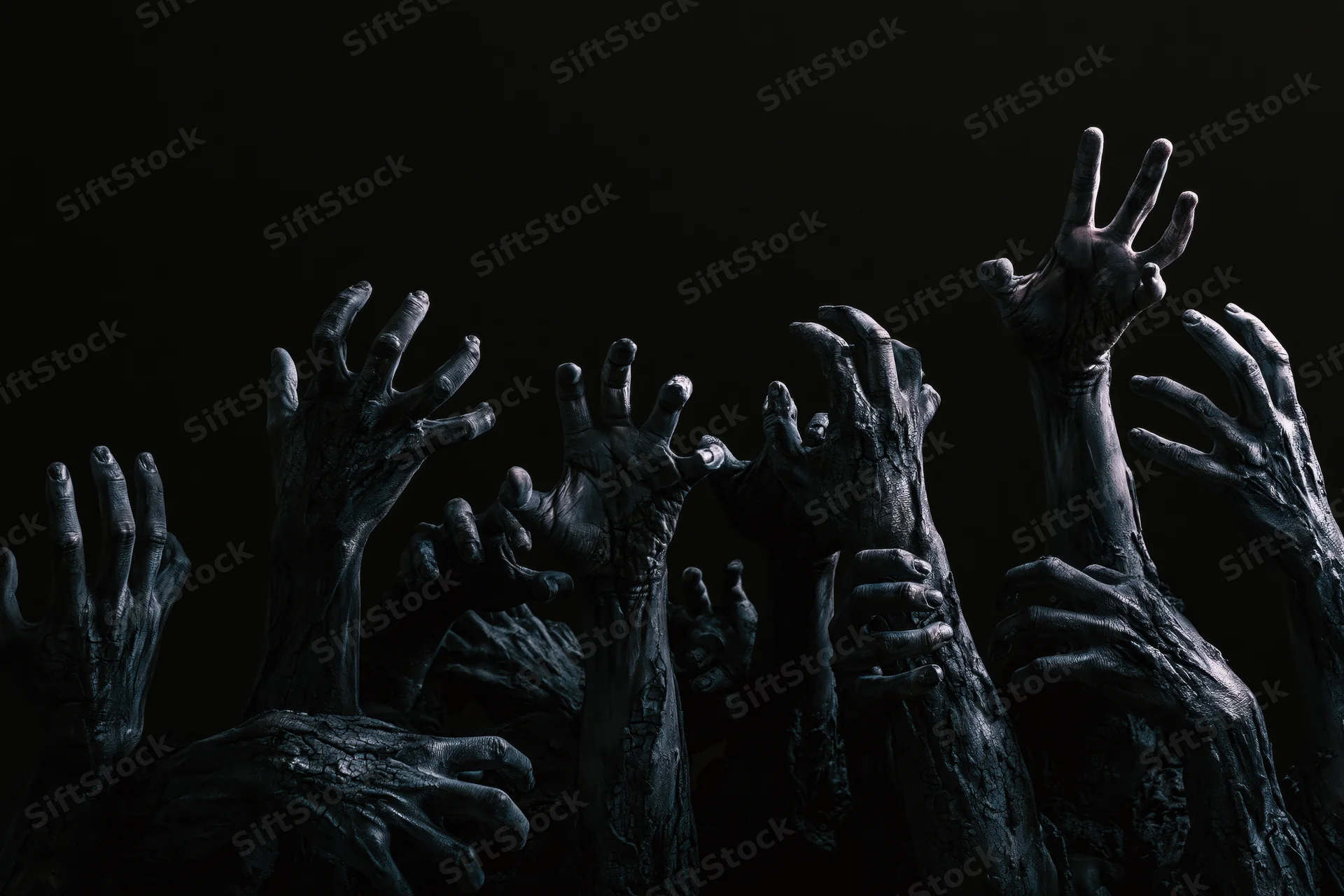 Decayed zombie hands reaching upward from darkness