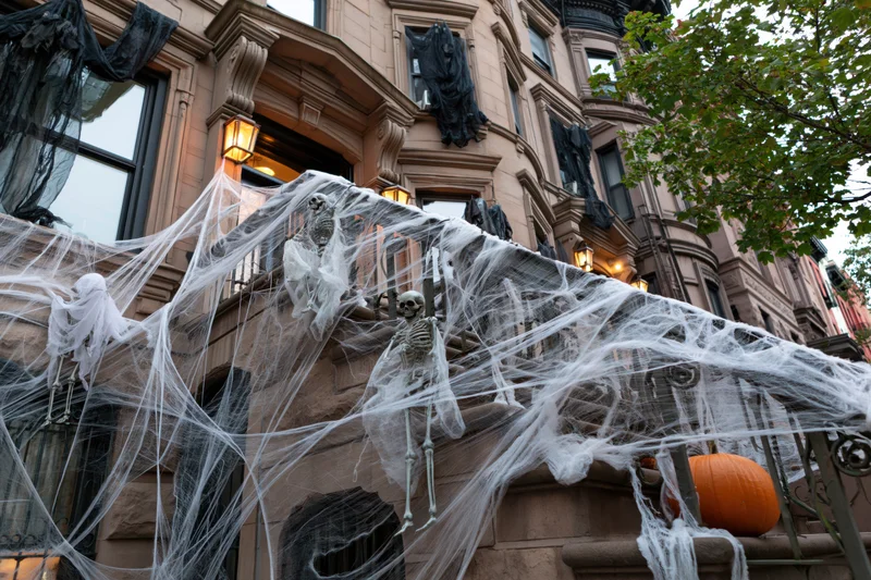 Halloween-decorated brownstone stoop with skeletons and spiderwebs in new york city