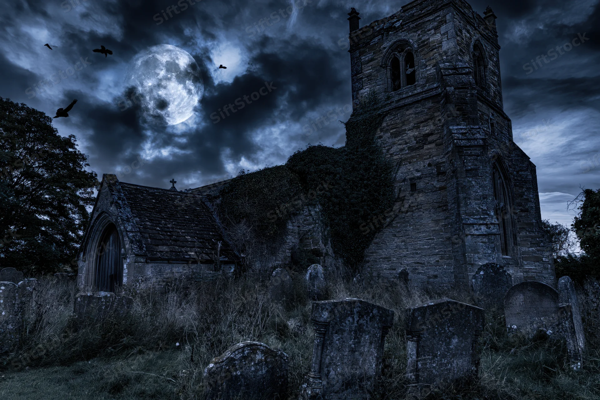 Old stone church with bell tower surrounded by tombstones under a full moon at night