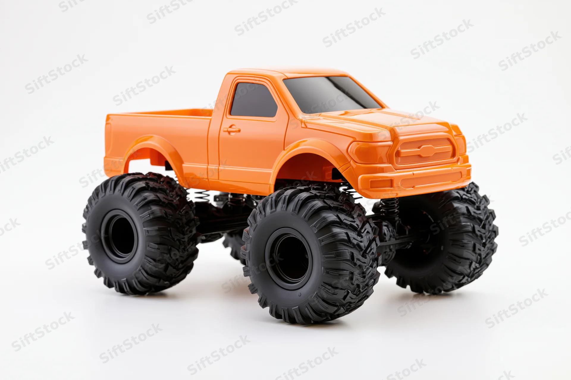 Orange monster truck toy with oversized black knobby tires on white background