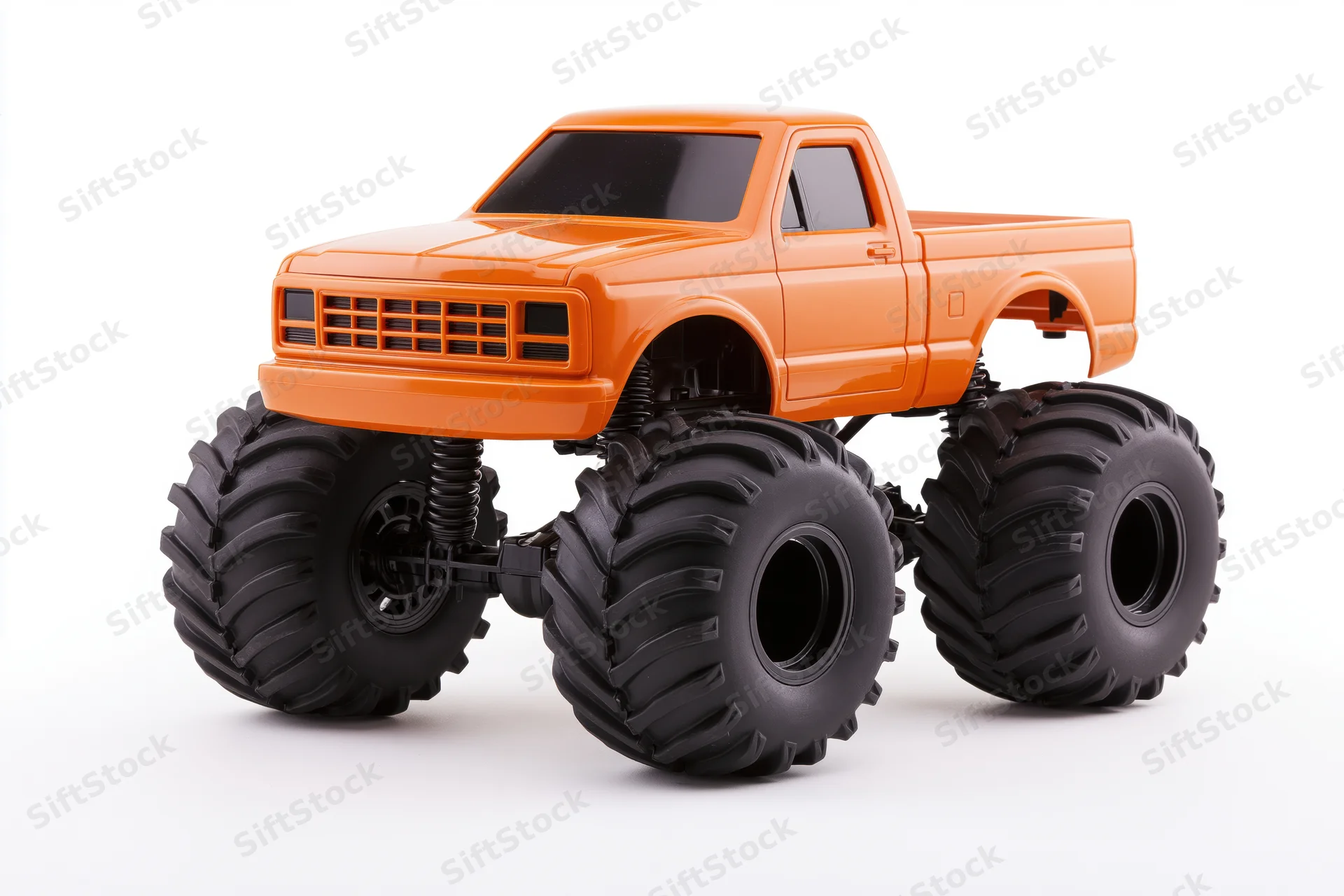 Orange monster truck toy with oversized black knobby tires on white background