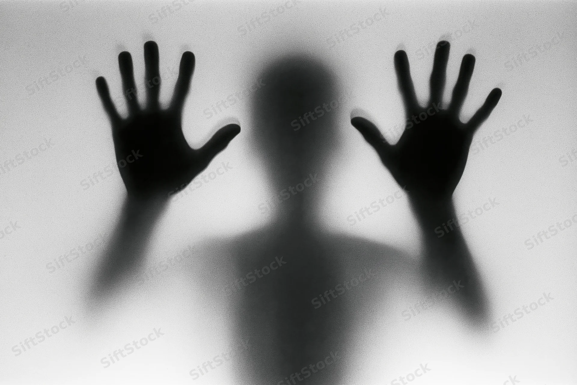 Silhouette of a person pressing hands flat against frosted glass