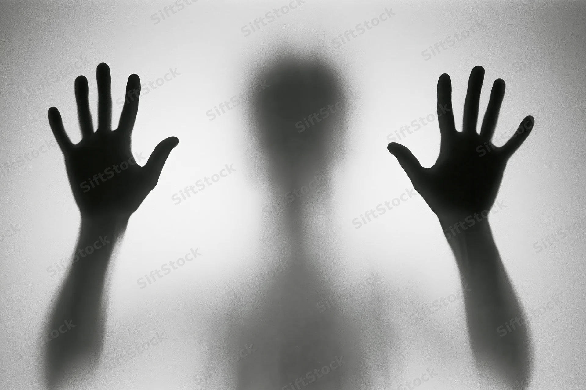 Silhouette of a person pressing hands flat against frosted glass