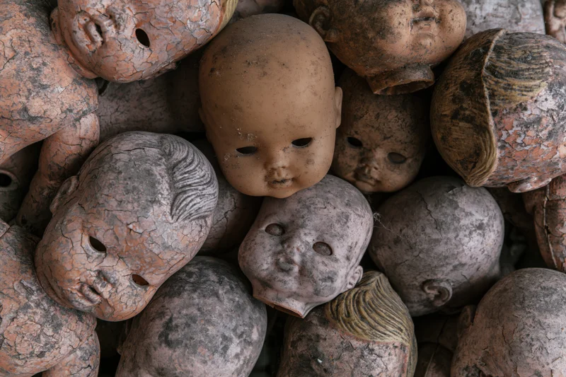 Decayed vintage baby doll heads piled together in a heap