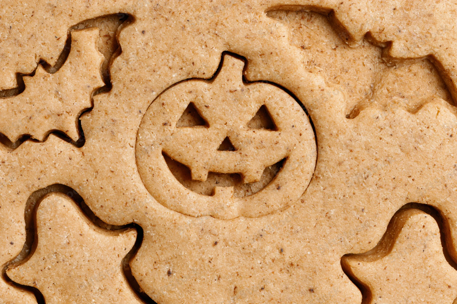Raw gingerbread dough with halloween shapes cut out, close-up view