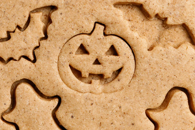 Raw gingerbread dough with halloween shapes cut out, close-up view