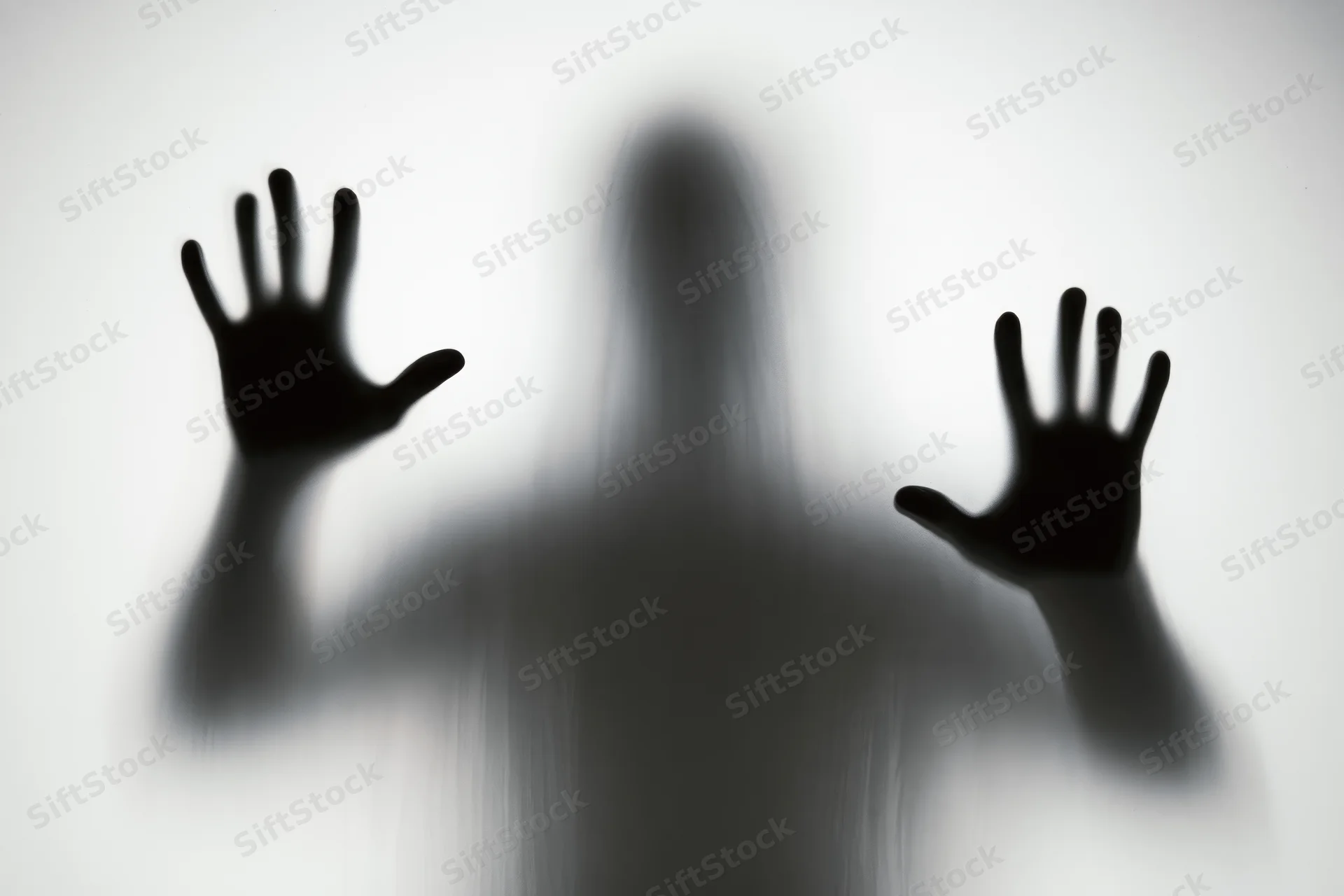 Shadowy silhouette of a person pressing hands flat against frosted glass