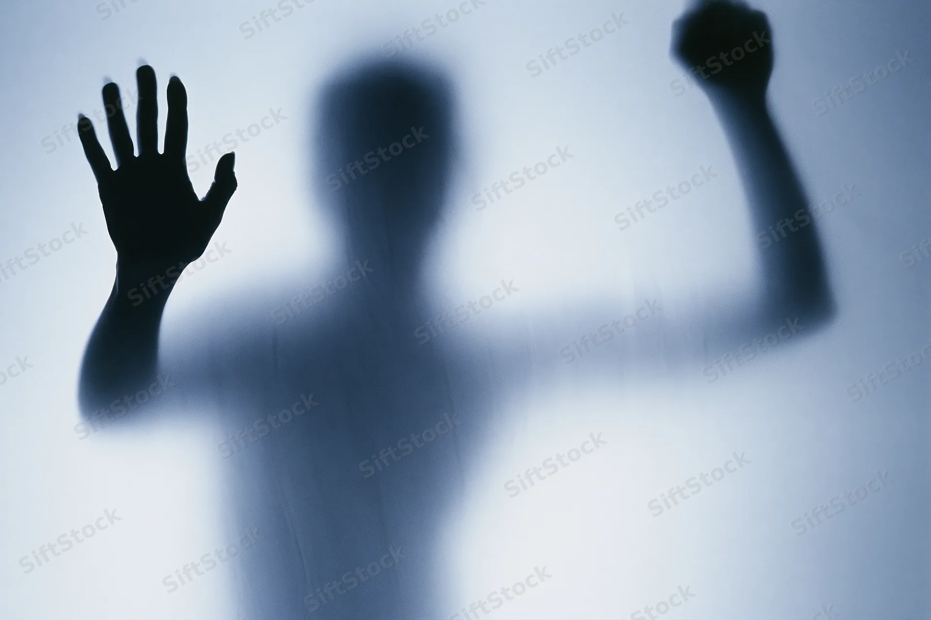 Silhouette of a woman pressing one hand flat against frosted glass with the other raised in a fist