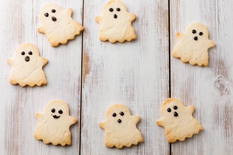 Ghost-shaped shortbread cookies arranged on a light wooden surface