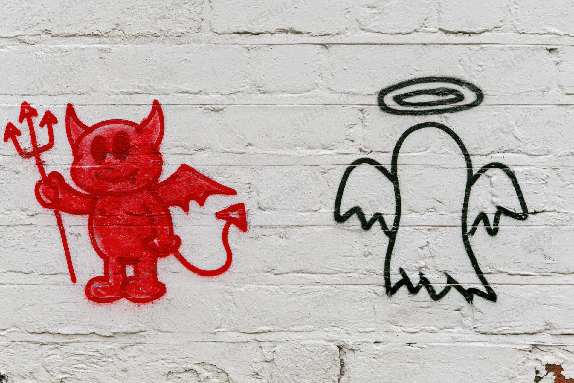 Red devil and black angel graffiti on white brick wall
