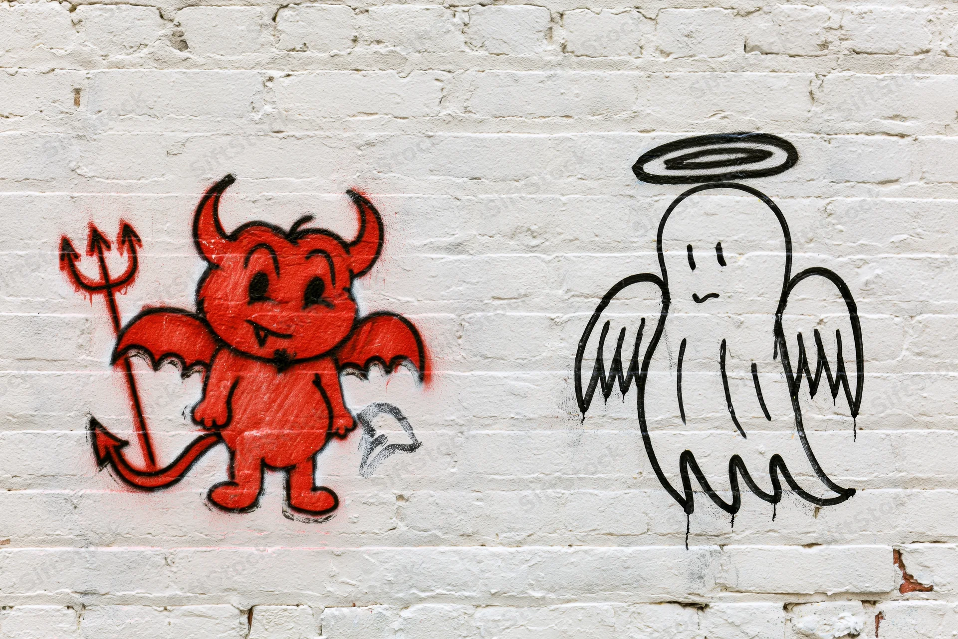 Red devil and black angel graffiti figures on white brick wall