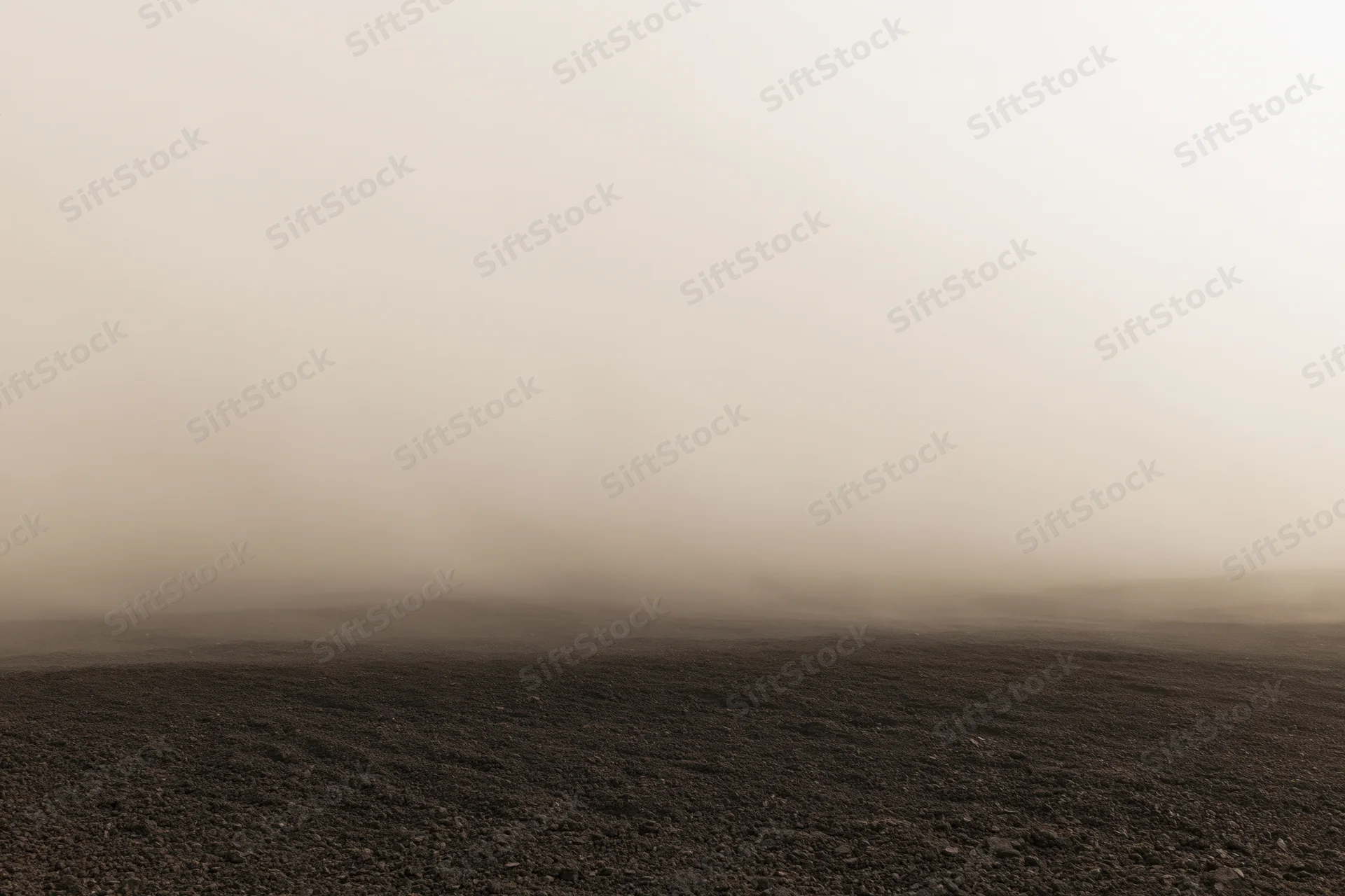 Thick dust cloud rolling low over dark rocky ground